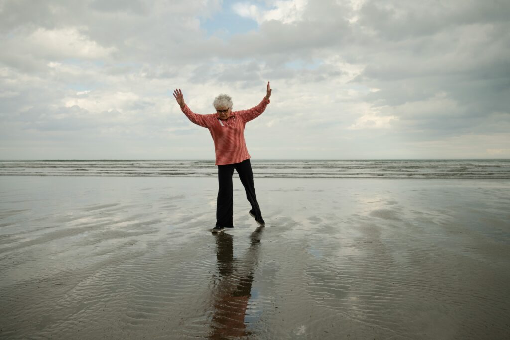 Senior oefent evenwicht op één been voor valpreventie op het strand